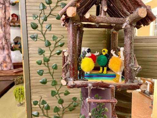 Small toys in a treehouse with circles of different colours on their stomachs